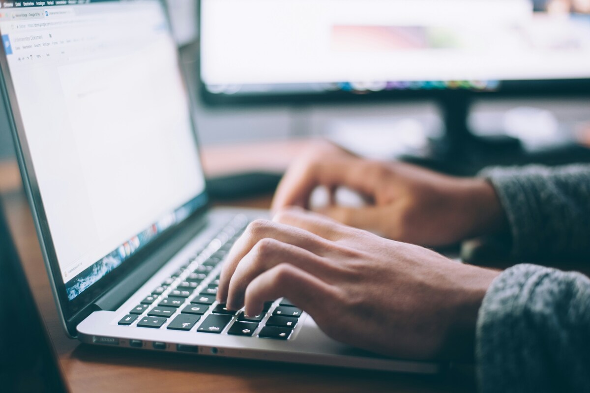 Person working at a computer receiving technical assistance